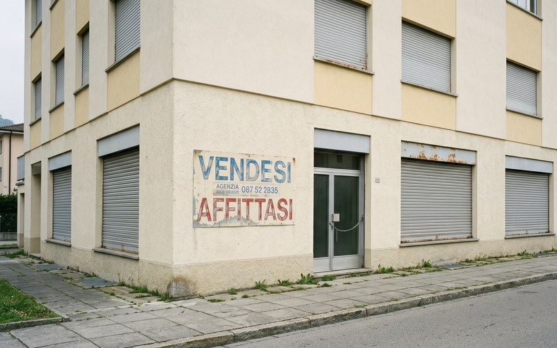 TicinoNews — Lugano e il valore strategico degli edifici dismessi: dalla vendita alla rendita pubblica · Edificio commerciale ticinese vuoto con scritte 'Vendesi · Affittasi'